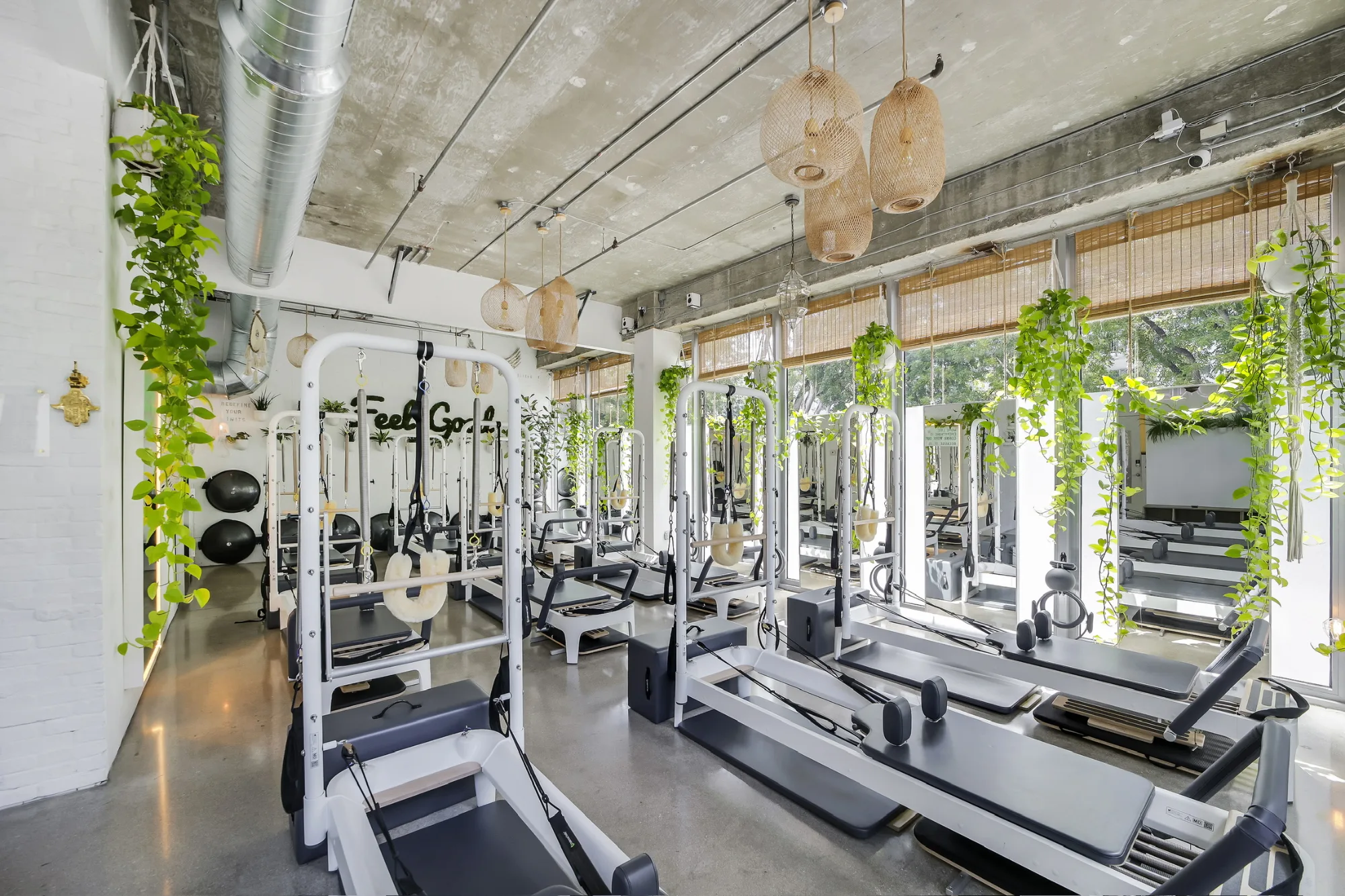 Bright, plant-filled Pilates One reformer studio with reformer machines in rows and natural light from large windows